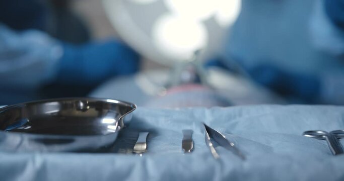 Close-up of nurse taking medical instruments for operation with colleagues performing in background