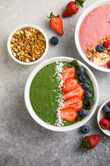 Matcha green tea breakfast superfoods smoothies bowl topped with strawberries, blueberries, coconut flakes Overhead, top view, flat lay
