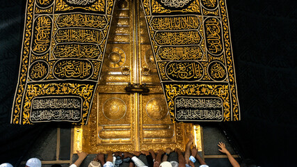 Hands of people praying at the golden gate of the Kaaba