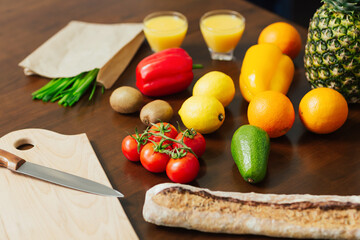 Fresh vegetables, fruits, knife and cutting board for cooking dinner on wooden background.