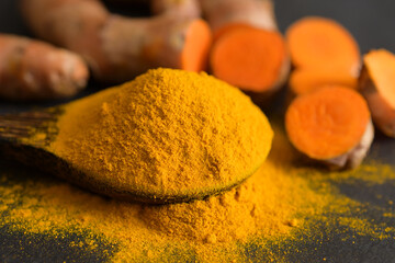 Turmeric powder and fresh turmeric (curcumin) on black background,spices,copy space.
