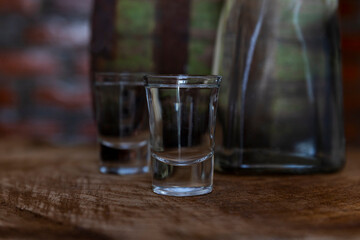 Hard alcoholic drink or brandy from fermented fruits, old wooden table, still life