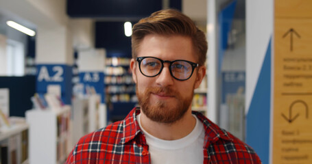 Close up of smiling hipster male student walking in library