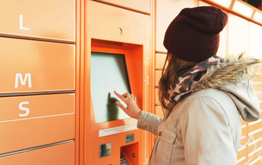 Woman picks up mail from automated self-service post terminal machine.