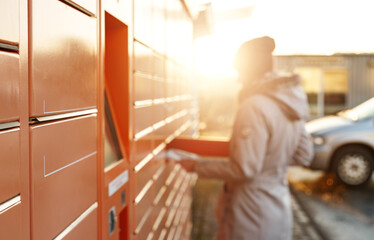 Woman picks up mail from automated self-service post terminal machine.