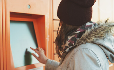 Woman picks up mail from automated self-service post terminal machine.