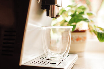 Brewing fresh coffee from the espresso machine. Preparing cappuccino in a glass transparent coffee cup.