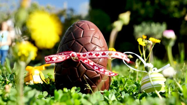 chocolate Easter egg and children running in the garden
