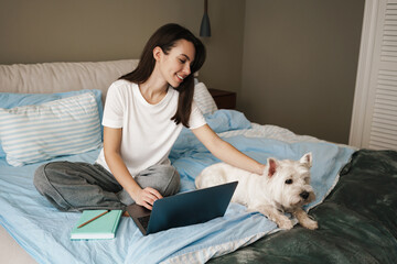 Happy young brunette woman stydying in bedroom