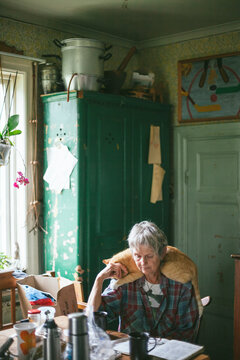 Senior woman sitting at table with cat on her shoulders