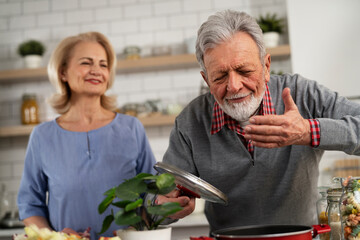  Senior woman and man cooking in the kitchen. Happy husband and wife preparing delicious food at home.