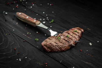 Rump Steak on fork on dark wooden background. banner, menu recipe place for text, top view