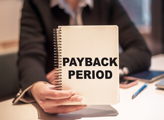 Business woman holds a notebook with the text PAYBACK PERIOD.