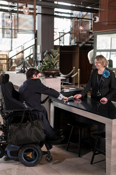 Businessman on wheelchair at hotel reception desk