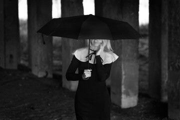 Mysterious girl in a black and white dress under an umbrella 