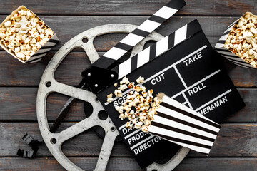 Popcorn with clapperboard and movie film reel. Cinema background