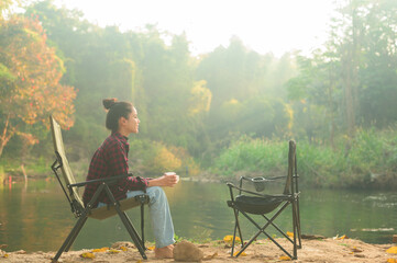 Beautiful young traveler woman is enjoying with nature drinking coffee in the morning over lake, relaxation , camping holiday and travel concept ..