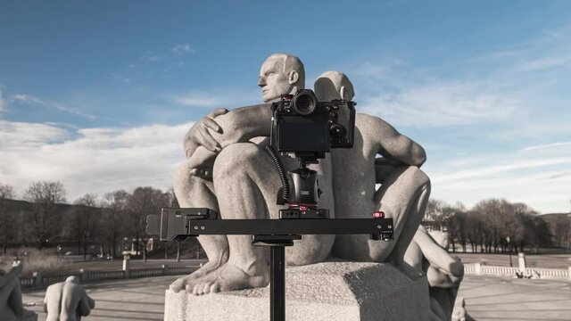 Compact Camera On Slider Shooting Granite Sculpture Of Two Men Sitting Back To Back With Crossed Arms On Pedestal At Frogner Park, Oslo, Norway. - timelapse