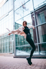 girl in flight, jumping, dancing in the street, wearing a coat and black jeans