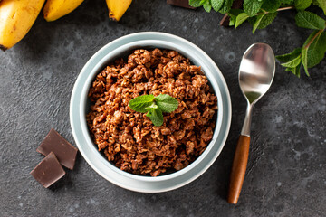 Chocolate oatmeal porridge with banana in bowl, decorated mint. Top view