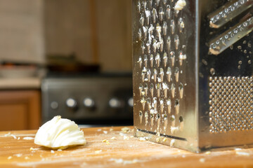 Half of the boiled egg lies on a wooden board near the grater close up