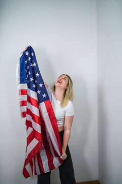 Chica guapa rubia con bandera americana feliz celebrando 4 de julio
