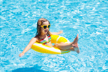 Child in swimming pool on ring toy. Kids swim.