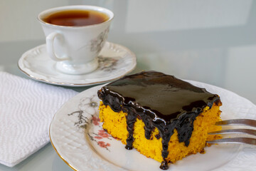 carrot cake with chocolate icing and cup of tea