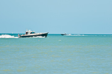 two powerboats speeding across tropical waters , going in opposite direction creating a wake on a winter day