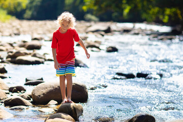 Child hiking in mountains. Kids at river shore.