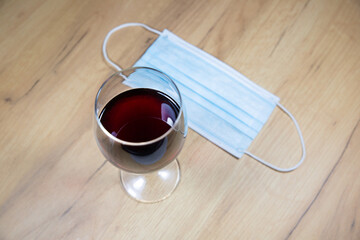 Medical mask near the a glass of wine. Alcoholic addict, Lost job, unemployment concept, economic crisis. Depression and alcoholism. Coronavirus (COVID-19)