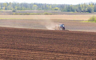 tractor plows the field on a sunny spring day