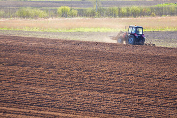 tractor plows the field on a sunny spring day