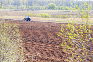 tractor plows the field on a sunny spring day