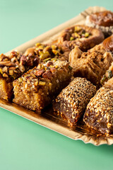 Assortment of Ramadan dessert baklava on green background