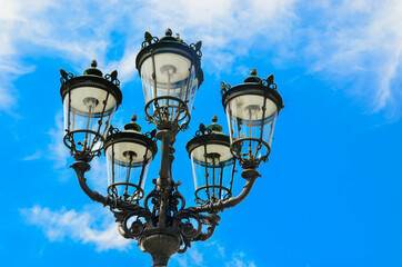 Fototapeta na wymiar Forged black old beautiful lantern on a blue sky background