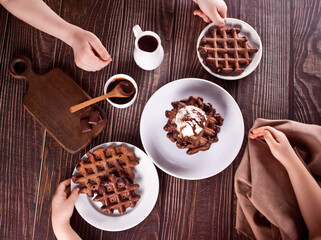 Homemade chocolate waffles with ice cream decorated chocolate syrup. Kids eating a waffles. Top view.