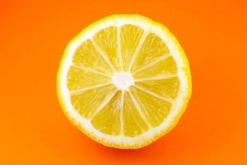 Fototapeta na wymiar Close up photo of lemon texture on the orange background. Fruit cut in half, inside, macro view. Minimalism, original beautiful wallpaper photo.