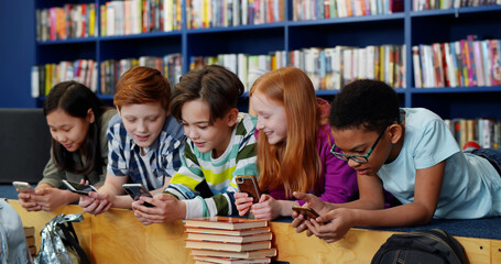 Multiethnic students using mobile phone in library at school