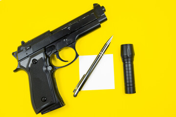 Black gun, reminder note paper, pen and flashlight lies on a yellow background. Private detectives...