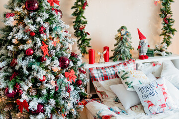 Christmas tree with red balls, bed with festive decor in the interior.