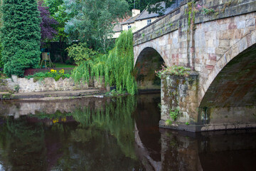 Fototapeta na wymiar Stone Bridge over river with green plants