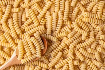Wooden spoon with pasta. Fusilli pasta background