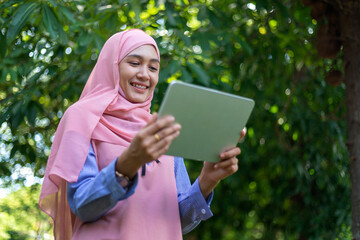Happy beautiful and cheerful Asian Muslim women wear a hijab, wave their hands to the camera and...
