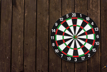Dart board on dark wood background with copy space. A dart in the bull's-eye. Achieving the goal....