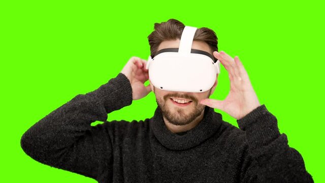 Happy excited man puts on white virtual reality VR goggles first time impressive world experience headset immersive playing movie watching green screen chroma key XR augmented quest 2 technology nerd