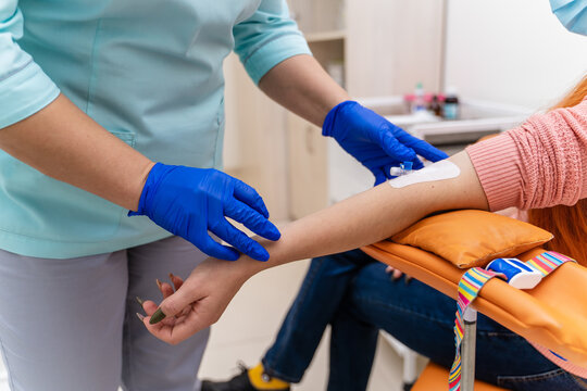 An unrecognizible doctor with syringe is taking blood for test. Selective focus on part of an arm. Clinic background.
