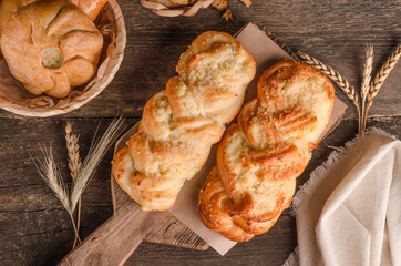 Fresh baked goods - delicious wicker buns on wooden background