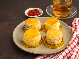 English style scones delicious freshly baked homemade and strawberry jam on a plate with a cloth placed on the old kitchen table. Top view with copy space for text. Flat lay
