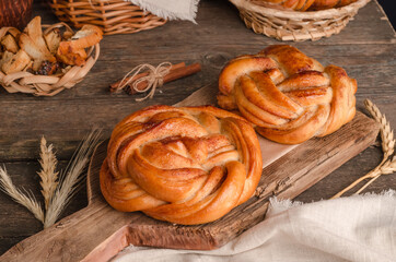 Fresh baked goods - delicious wicker buns with cinnamon on a wooden